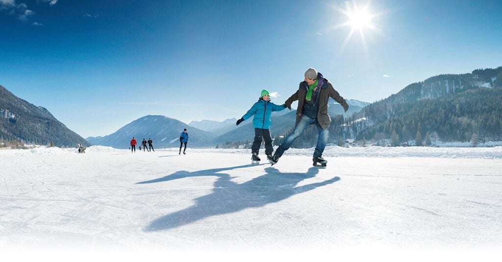 Vader en zoon die aan het schaatsen zijn op een bevroren meer