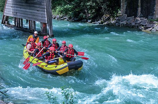 Een groep mensen die in een gele rubberboot aan het raften is op een wilde rivier