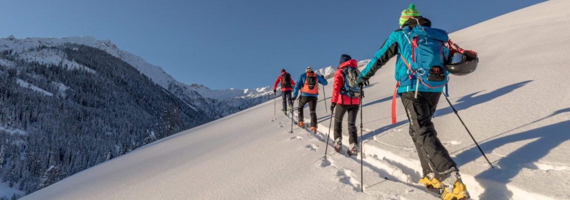 Een groep mensen die aan het langlaufen zijn op een bergrug bedekt met sneeuw