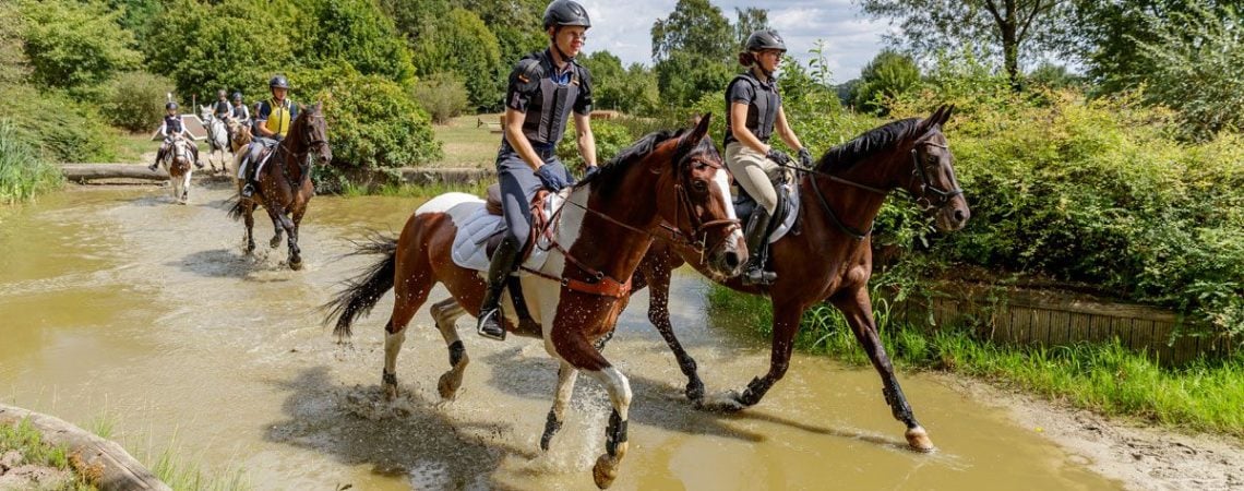 een groep mensen die een buitenrit maken op paarden