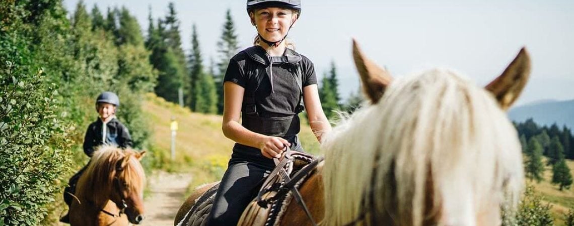 Een meisje en jongen die op pony's een buitenrit maken in de bergen